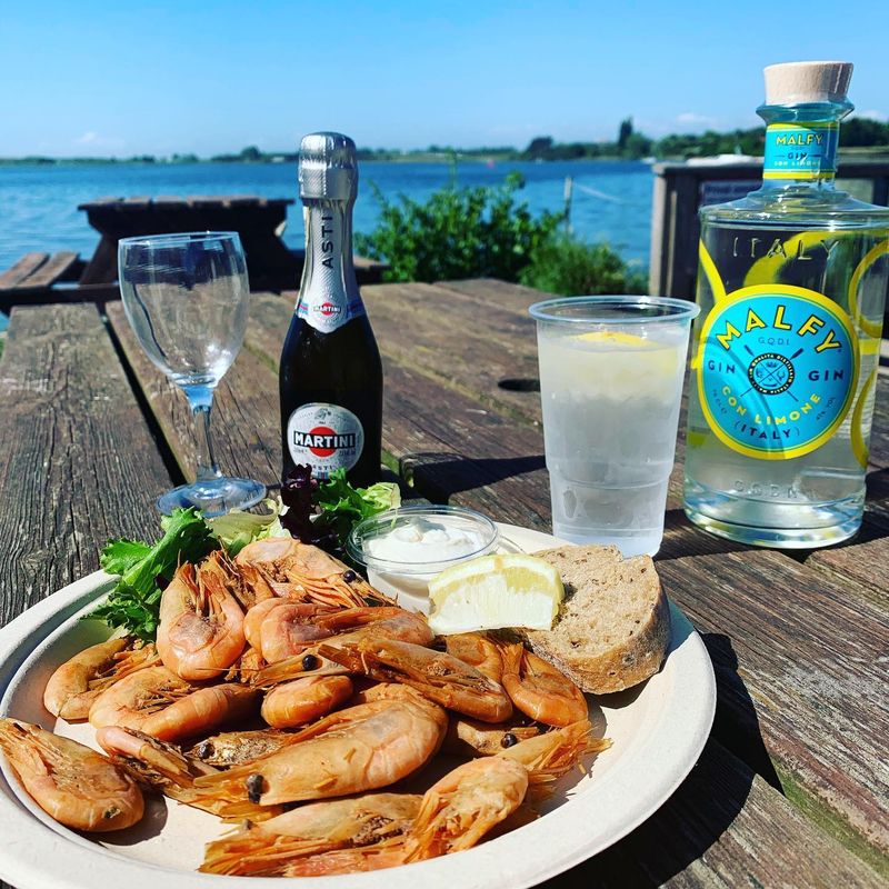 Rejer med brød og dressing, serveret med drinks på terrassen ved vandet