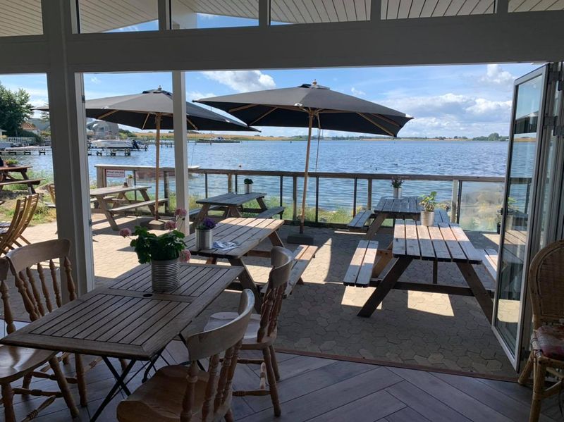 Caféen med åbne døre ud til terrassen og parasollerne ved vandet